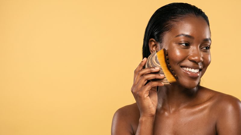 Femme souriante avec sa brosse de drainage visage